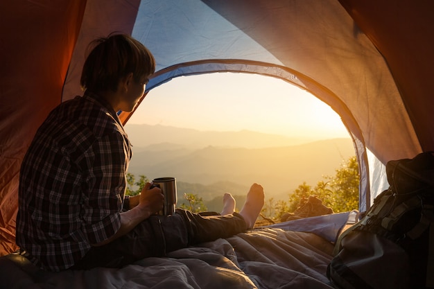 Бесплатное фото Молодой человек сидит в палатке с чашкой кофе