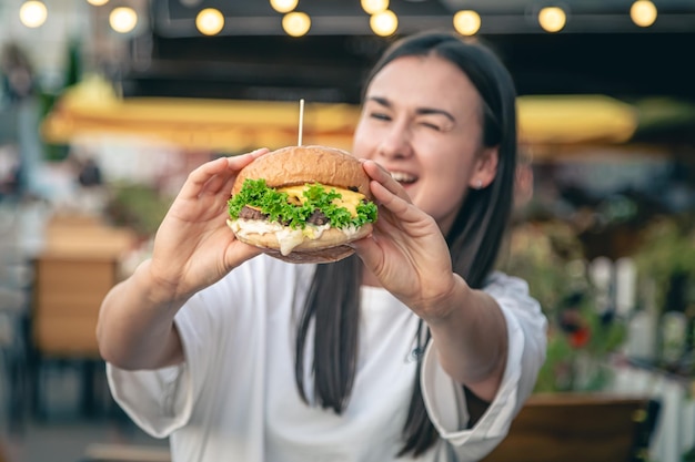 無料写真 ストリートカフェでハンバーガーを食べる若い女性