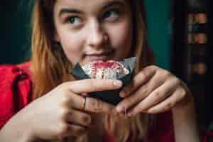 Бесплатное фото Молодая женщина наслаждается малиновым кексом в кафе
