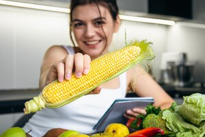 Молодая женщина на кухне с блокнотом и кукурузой в руке