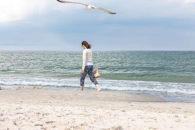 무료 사진 젊은 여자가 바다를 걷고 있다