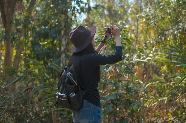 Молодая женщина-треккер фотографирует природу с камерой в лесу, отдыхает и путешествует.
