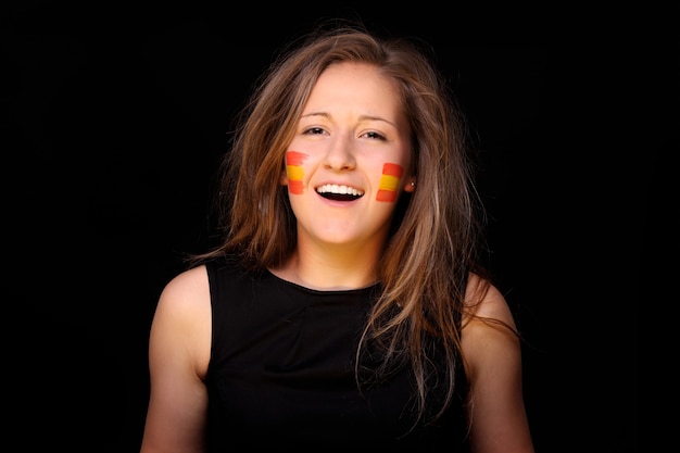 Молодая женщина с испанскими флагами на щеках стоит над черным