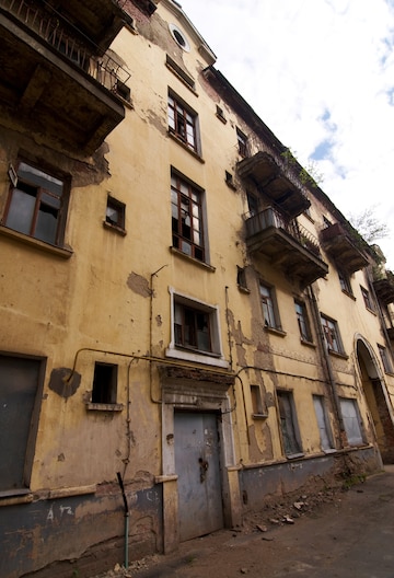 Prédio de 4 andares mal-cuidado, com janelas e portas quebradas