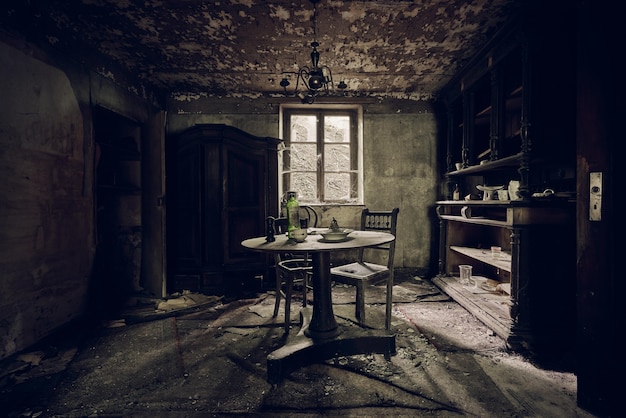 Abandoned room with a table in the middle and shelves against a wall near the window