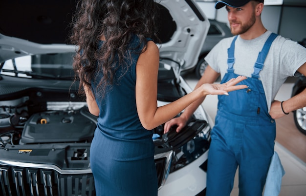 About that crash. Woman in the auto salon with employee in blue uniform taking her repaired car back