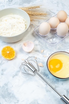 그릇에 있는 흰 밀가루와 스테인리스 요리 도구 계란 레몬 조각이 투톤 배경 위에 있는 보기