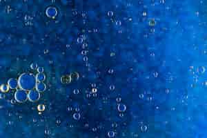 Free photo abstract blue background with oil bubbles floating on water surface