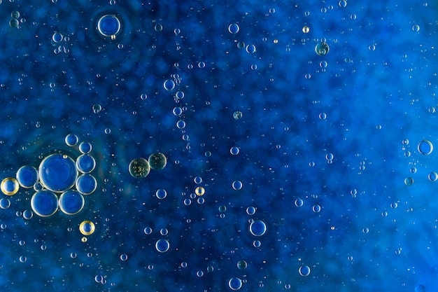 Abstract blue background with oil bubbles floating on water surface