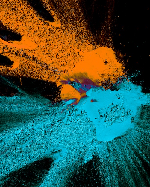 Abstract blue and orange color powder splatted on black background