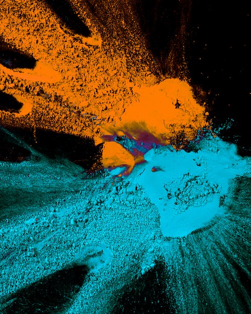 Abstract blue and orange color powder splatted on black background