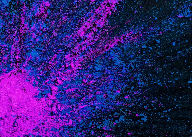 Abstract blue and pink dry holi colors splatted on black background