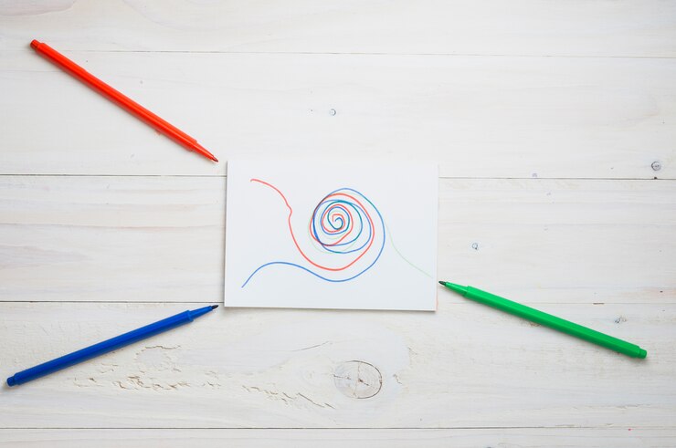 Free Photo abstract drawing on white paper with red; green and blue felt tip pen over wooden desk