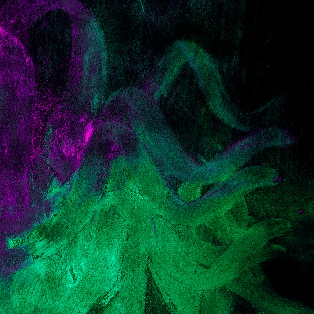 Abstract green and pink holi powder against black background