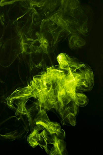 黒の背景に広がる抽象的な緑の煙