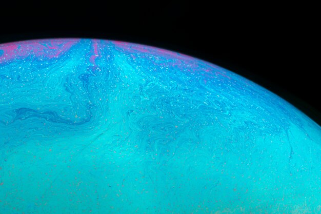 Abstract hued rippled soap bubble on black background