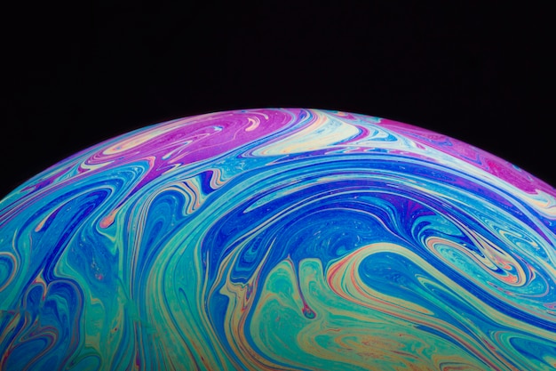 Abstract multicolored hued soap bubble on black background