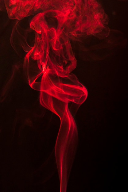 抽象的な赤いカール煙が黒の背景に立ち上がる