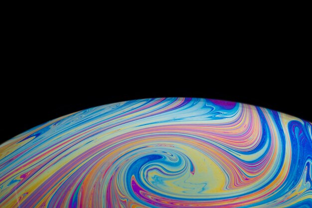 Abstract swirly colorful soap bubble on black background