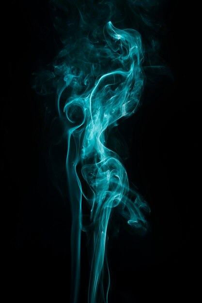 Abstract twirling turquoise smoke over the black background