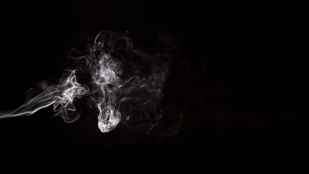 Abstract white smoke swirls over the black background