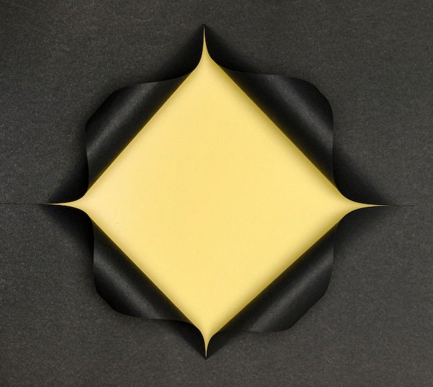 Abstract yellow shape on torn black paper