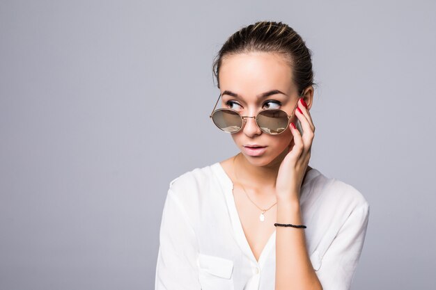 Accessories, eyewear, fashion, people and luxury concept - beautiful young woman in elegant black sunglasses over gray wall