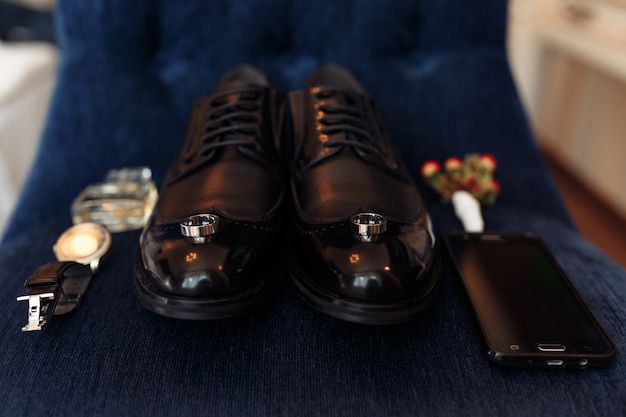 Accessories of a groom: shoes, boutonniere, phone, parfum and clock 
