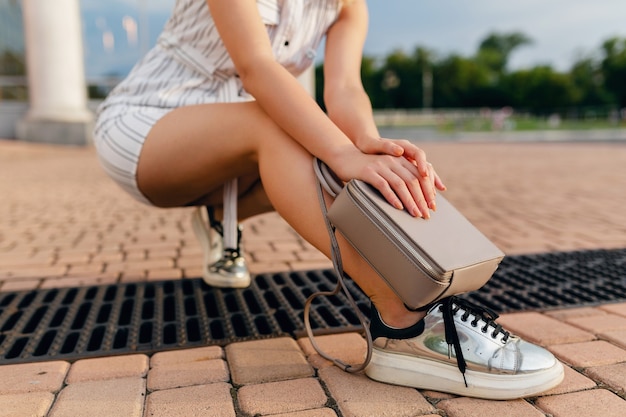 Free photo accessories of stylish woman walking in city street in summer fashion style dress, sneakers, grey purse handbag