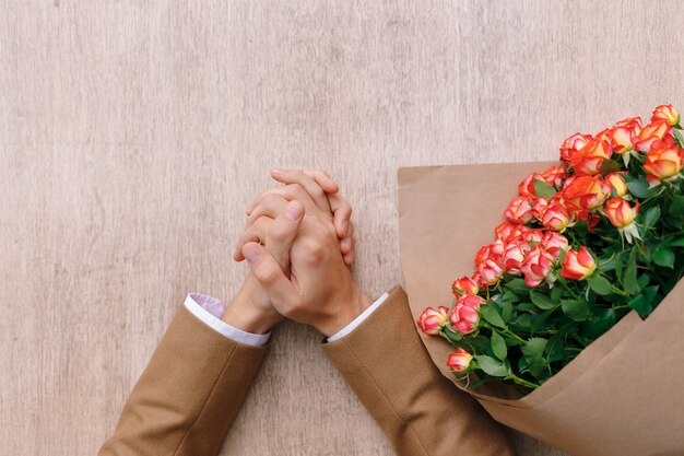 Free photo accurate man hands with crossed palms and a bunch of roses in cr craft paper