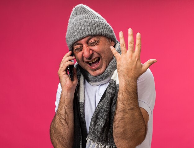 전화로 얘기하고 복사 공간이 분홍색 벽에 고립 손을 열어 유지하는 겨울 모자를 쓰고 목에 스카프와 함께 아프고 성인 아픈 백인 남자