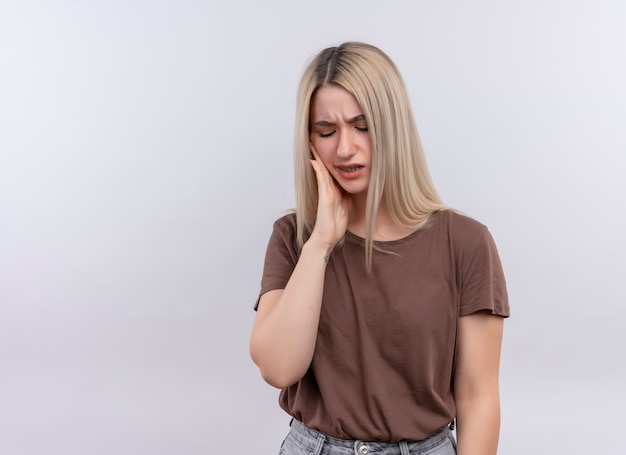 Aching young blonde girl putting hand on cheek having toothache on isolated white space with copy space