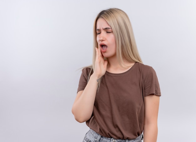 Aching young blonde girl with hand on cheek with closed eyes suffering from toothache on isolated white space with copy space