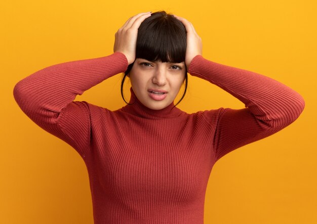 痛む若いブルネットの白人の女の子はオレンジ色の頭に手を置きます