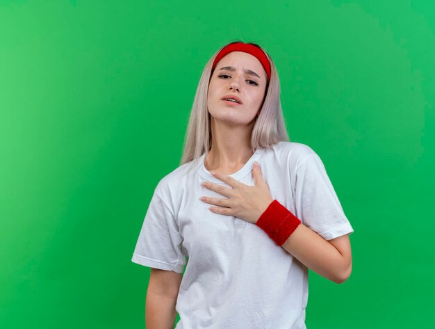 Aching young caucasian sporty girl with braces wearing headband