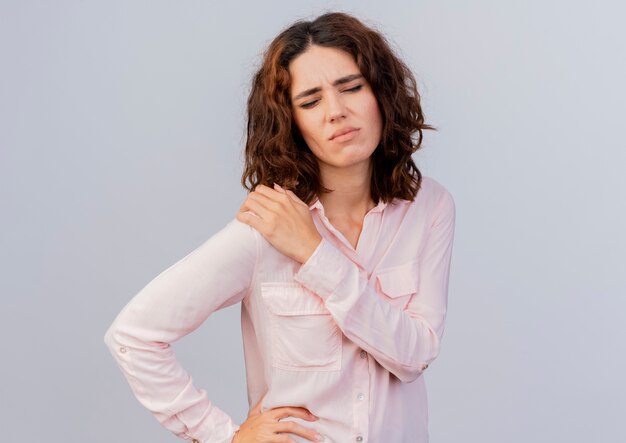 Aching young caucasian woman holds shoulder