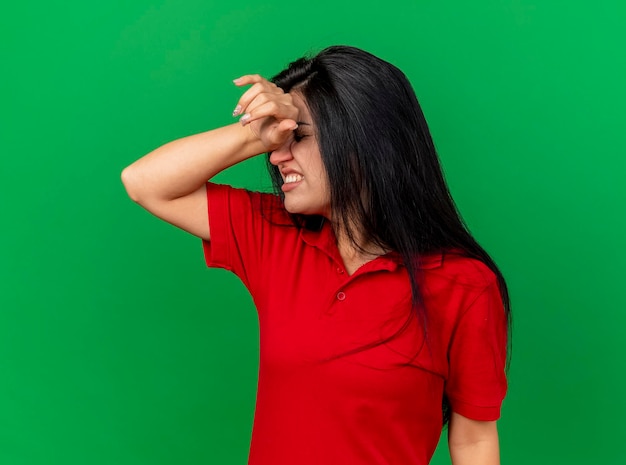 Free photo aching young ill woman putting hand on head with closed eyes suffering from headache isolated on green wall