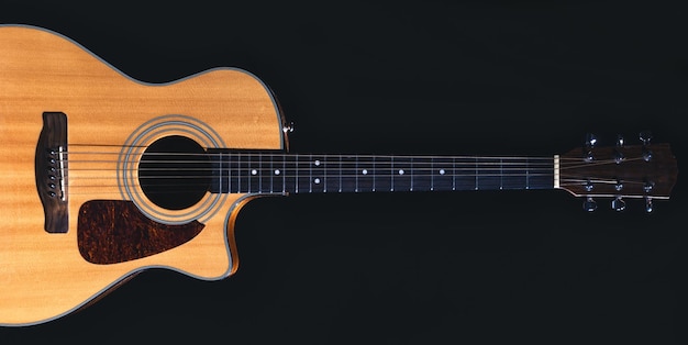 Acoustic guitar on a black background flat lay