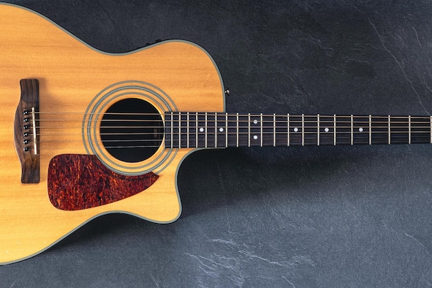 Free photo acoustic guitar on a black textured background top view