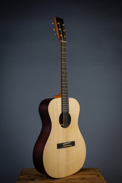 Acoustic guitar on a chair in black wall.