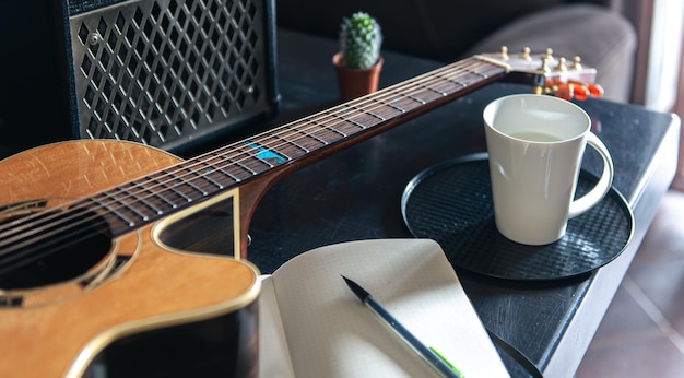 Acoustic guitar notepad and cup musical creativity concept