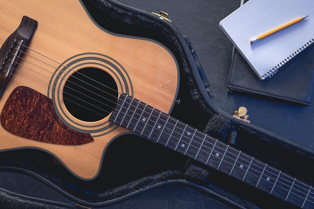 Acoustic guitar and notepad with pencil top view