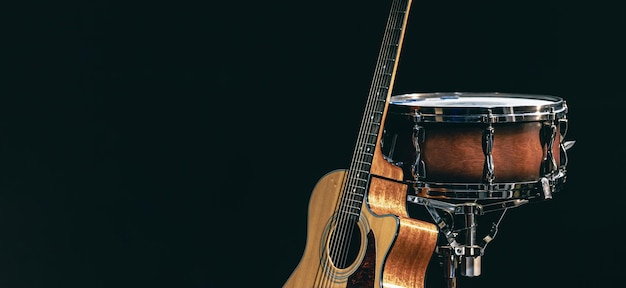 Foto gratuita chitarra acustica e rullante su sfondo nero isolato