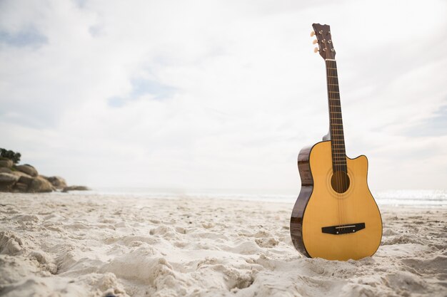 Acoustic guitar standing in the sand