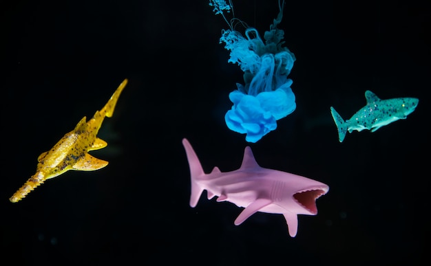 Acryllic color dissolving in water with toy sharks