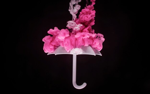 Acryllic pink color dissolving in water with plastic umbrella