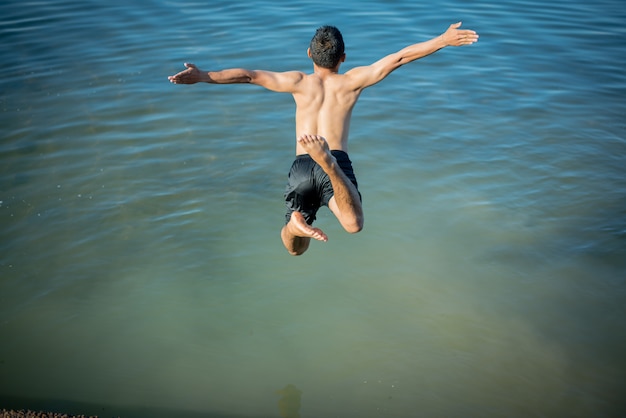 Активные мальчики прыгают из бревен в воду.