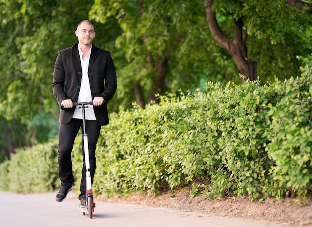 Активный бизнесмен езда скутер на открытом воздухе