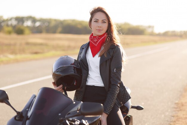 적극적인 여성 드라이버는 검은 빠른 오토바이에 앉아