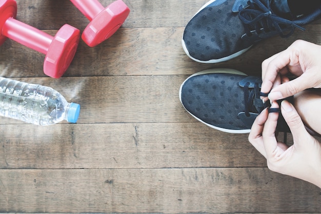 Foto gratuita mano femminile attiva con lo sport e la lavorazione di attrezzature, pian piano giaceva sul pavimento di legno